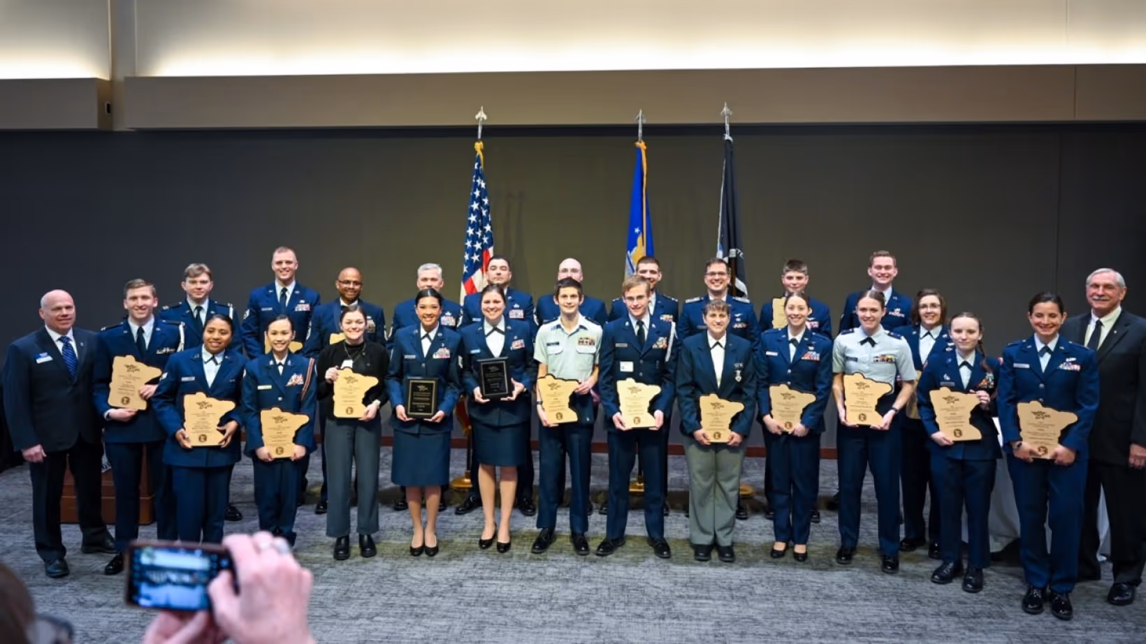 Group of uniformed Air Force members and officials holding awards, posing for a photo indoors.